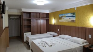Een hotelkamer met twee bedden, een kledingkast, een schilderij aan de muur en een klein tafeltje met een telefoon.