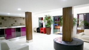 Een moderne lobby met een receptiebalie, een zithoek en grote ramen.