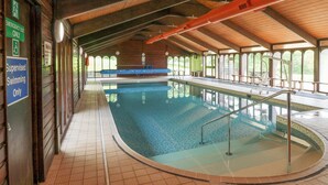 An indoor swimming pool with a tiled floor, a blue pool, and a wooden ceiling. - Harcombe House Bungalow 1 (Newton Abbot)