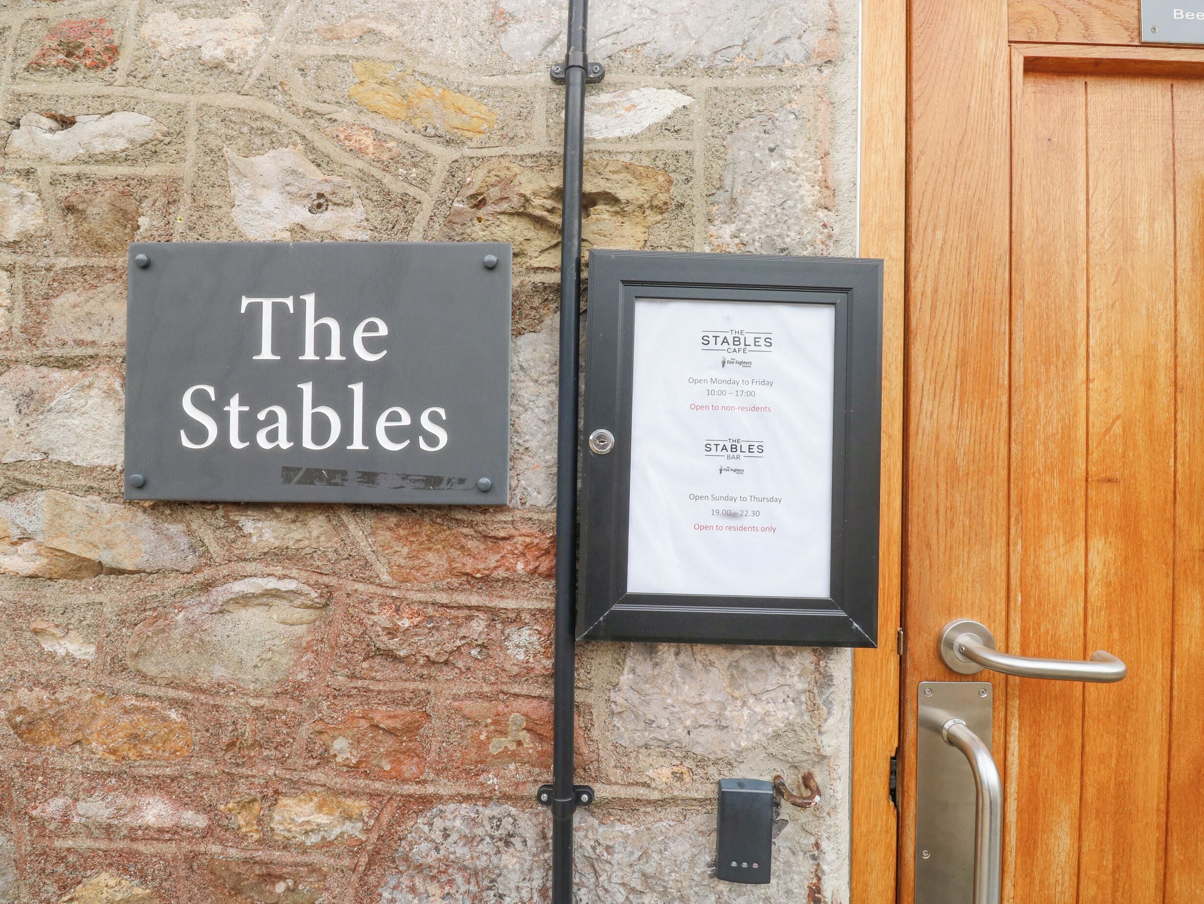 A sign for 'The Stables' cafe and bar, with operating hours displayed.