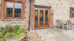 A stone building with a wooden door labeled "Games Room," a window, and outdoor seating. - Harcombe House Bungalow 1 (Newton Abbot)