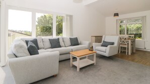 Un salon moderne avec un canapé gris, une table basse en bois et un coin repas comprenant une table et des chaises.