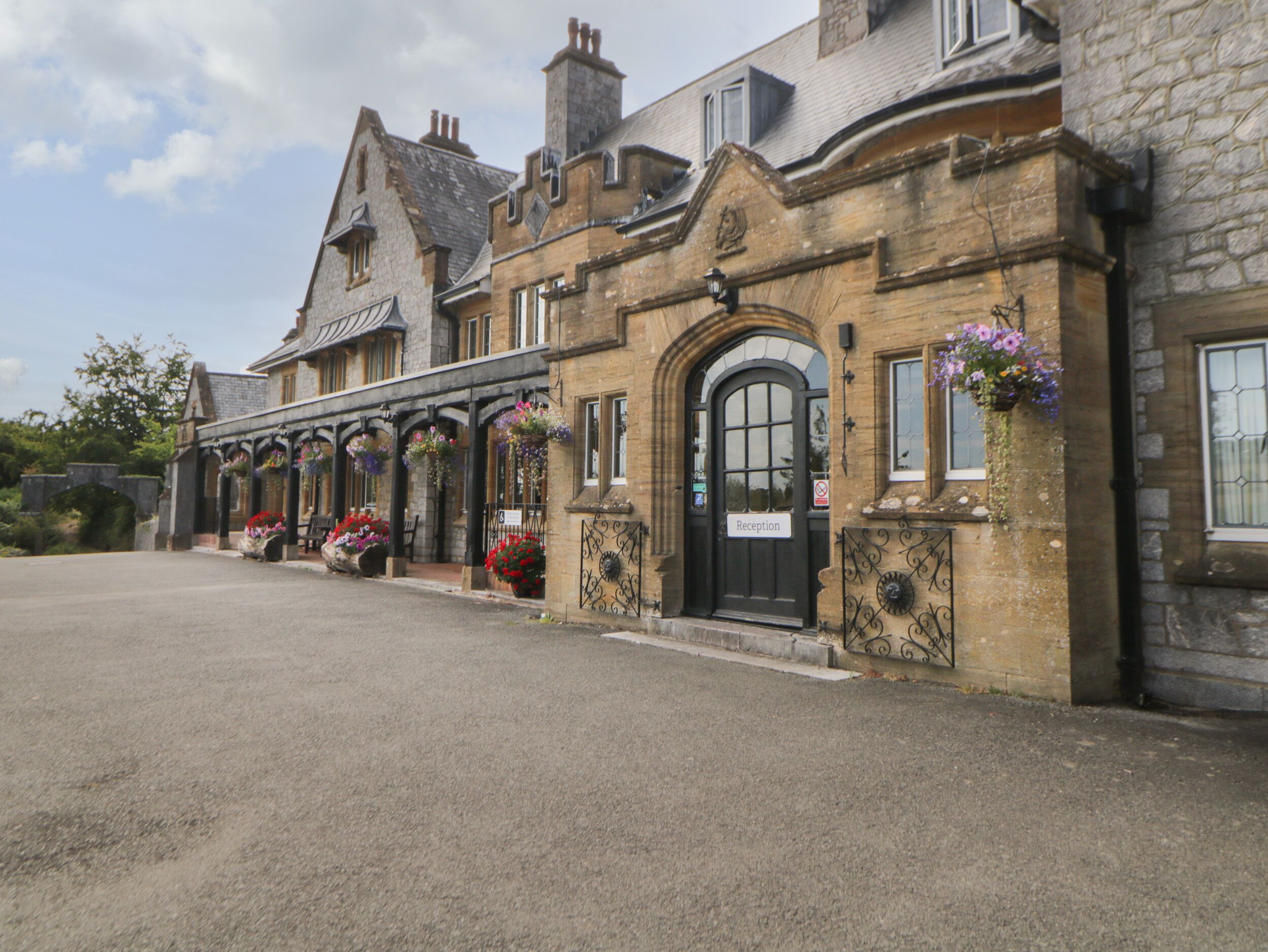 A historic building with a reception area, stone facade, and hanging flower baskets.