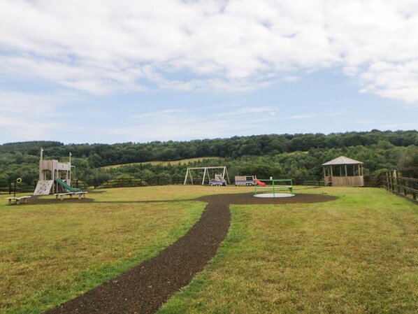 A playground with a slide, swings, and a small shelter.