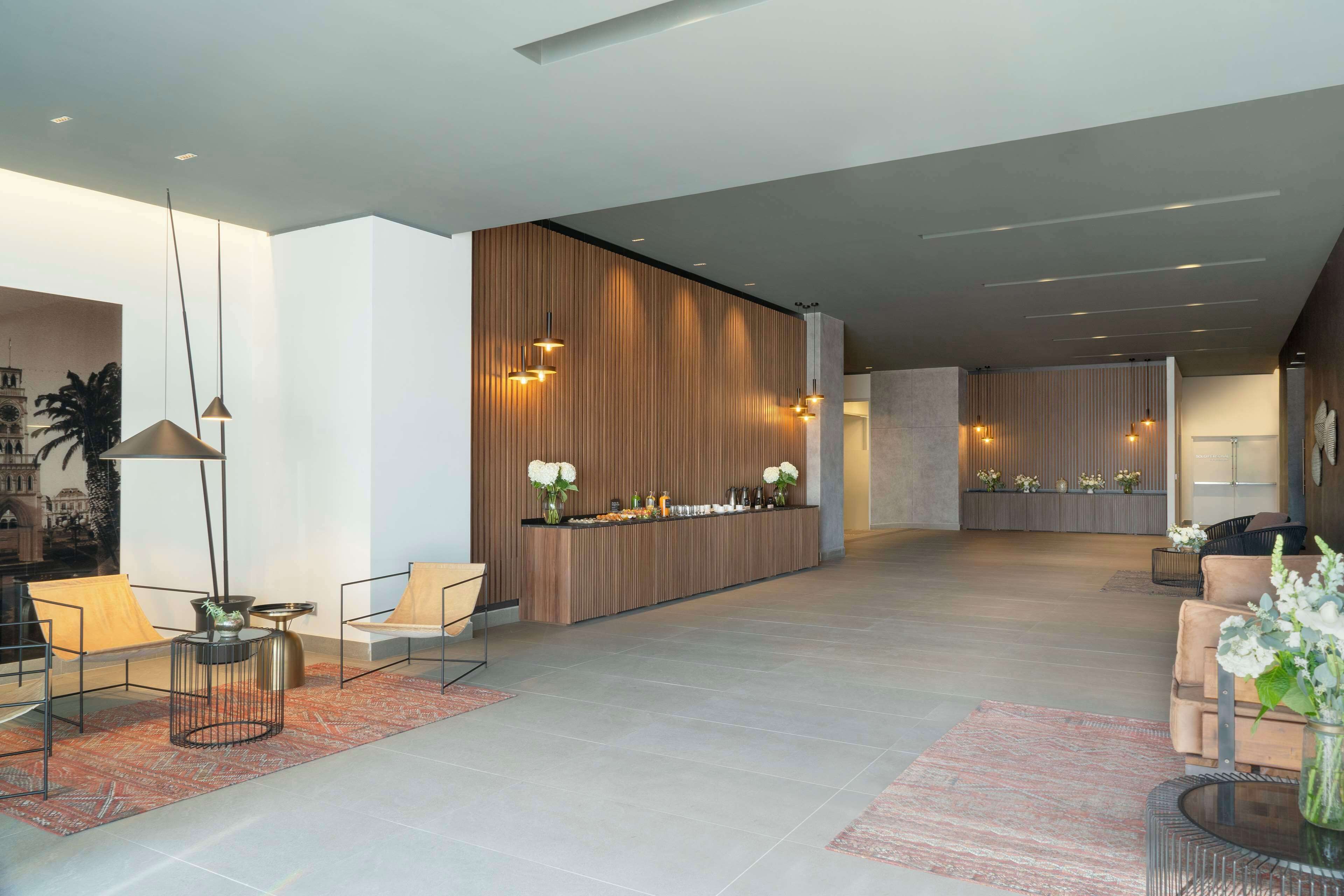 A modern lobby with a reception desk, seating areas, and a large window with a view of a building.