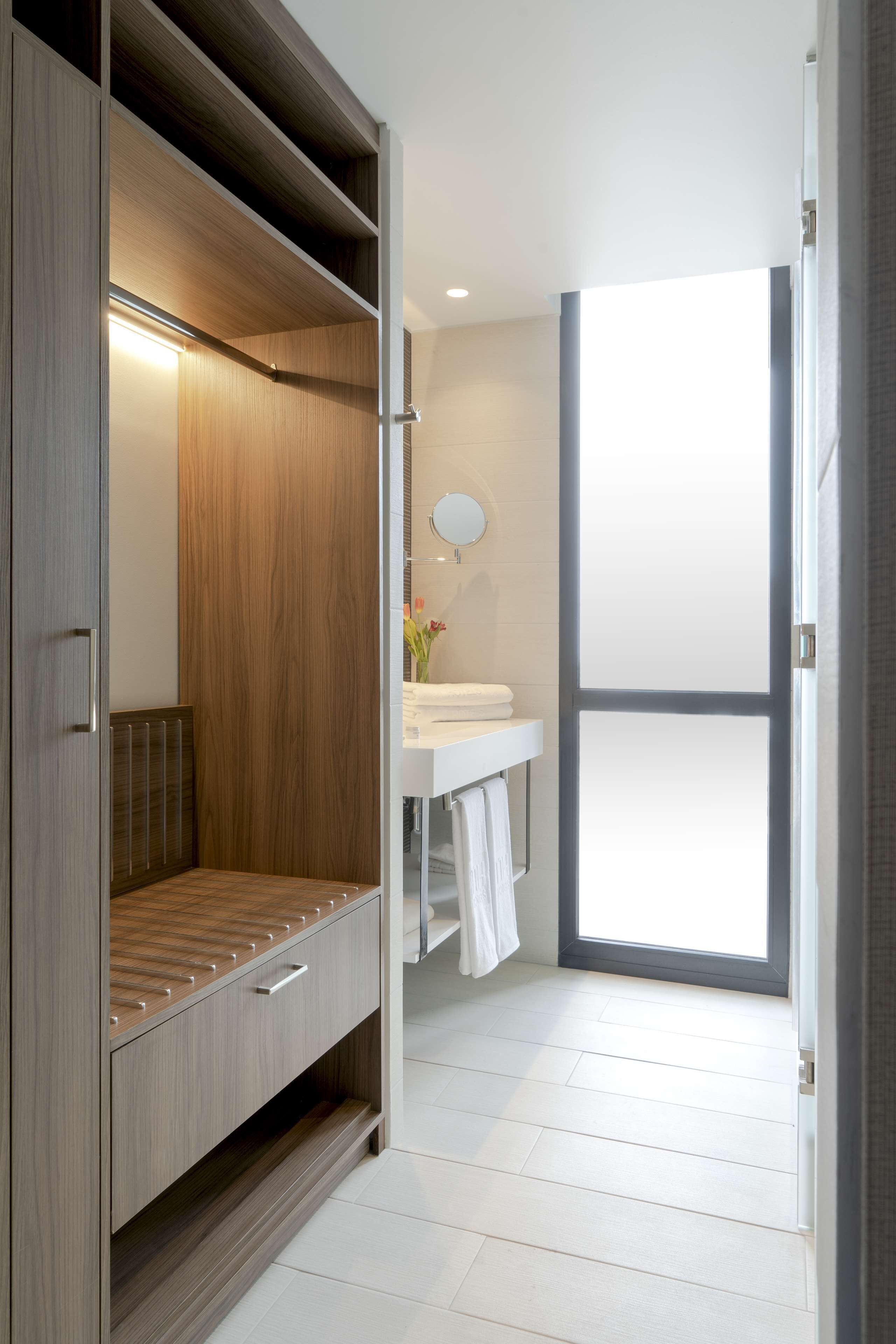A modern bathroom with a wooden vanity, a mirror, and a white sink.