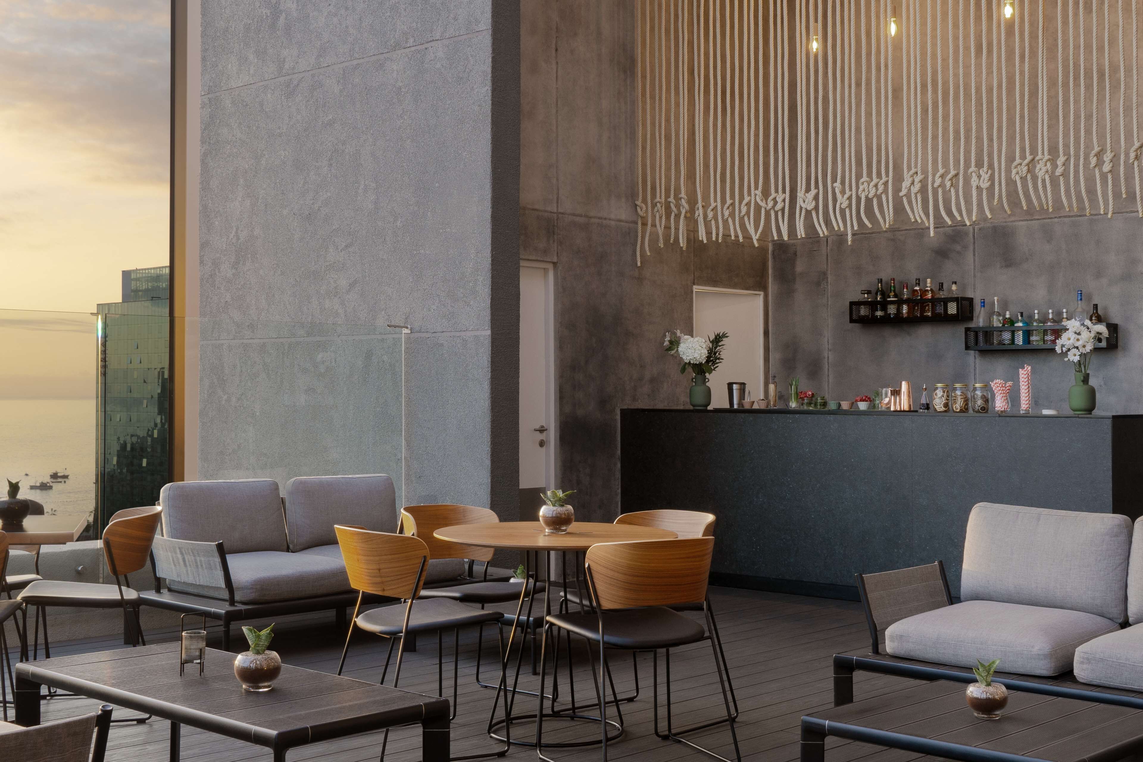 Un espacio exterior moderno con zona de bar y vista del horizonte urbano.