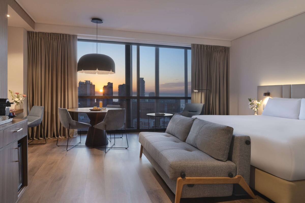 Een moderne hotelkamer met een groot bed, een bank, een bureau en een zithoek.