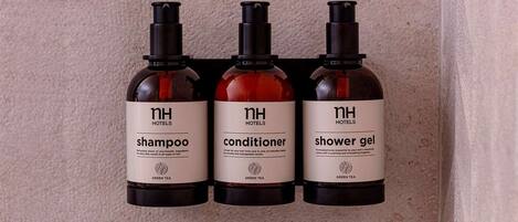 Three bottles of NH Hotels products: shampoo, conditioner, and shower gel.