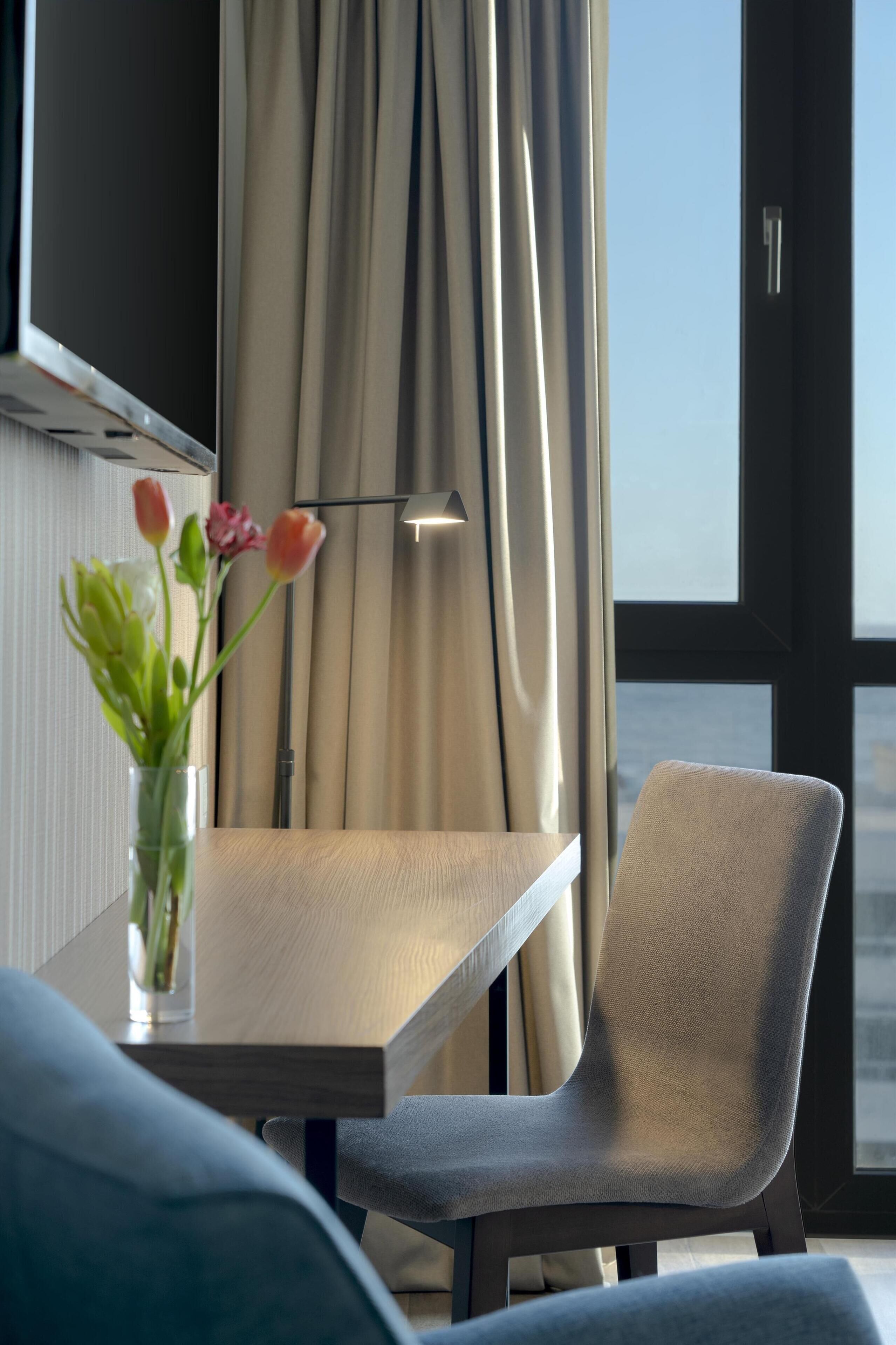 Un espace repas moderne avec une table en bois, un vase de fleurs et une chaise.