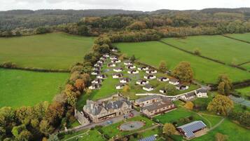 An aerial view of a residential area with multiple houses, a central building with a driveway, and solar panels.