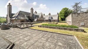 Un bâtiment en pierre doté d’une cour, d’un espace extérieur aménagé pour s’asseoir et offrant une vue sur le paysage environnant.