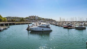 Un port de plaisance où sont amarrés de nombreux bateaux, un pont et des bâtiments en arrière-plan.