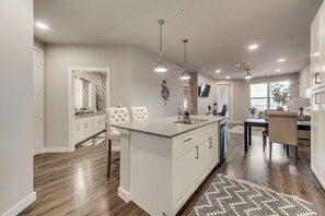 A modern kitchen with a central island, white cabinetry, and a dining area with a table and chairs.
