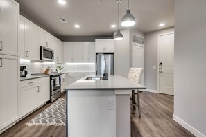 A modern kitchen with white cabinetry, stainless steel appliances, and a central island.