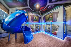 A room with a space-themed ceiling, a slide, and bunk beds. - Bohemian Chic Villa with Themed Bedrooms at Reunion (Kissimmee)