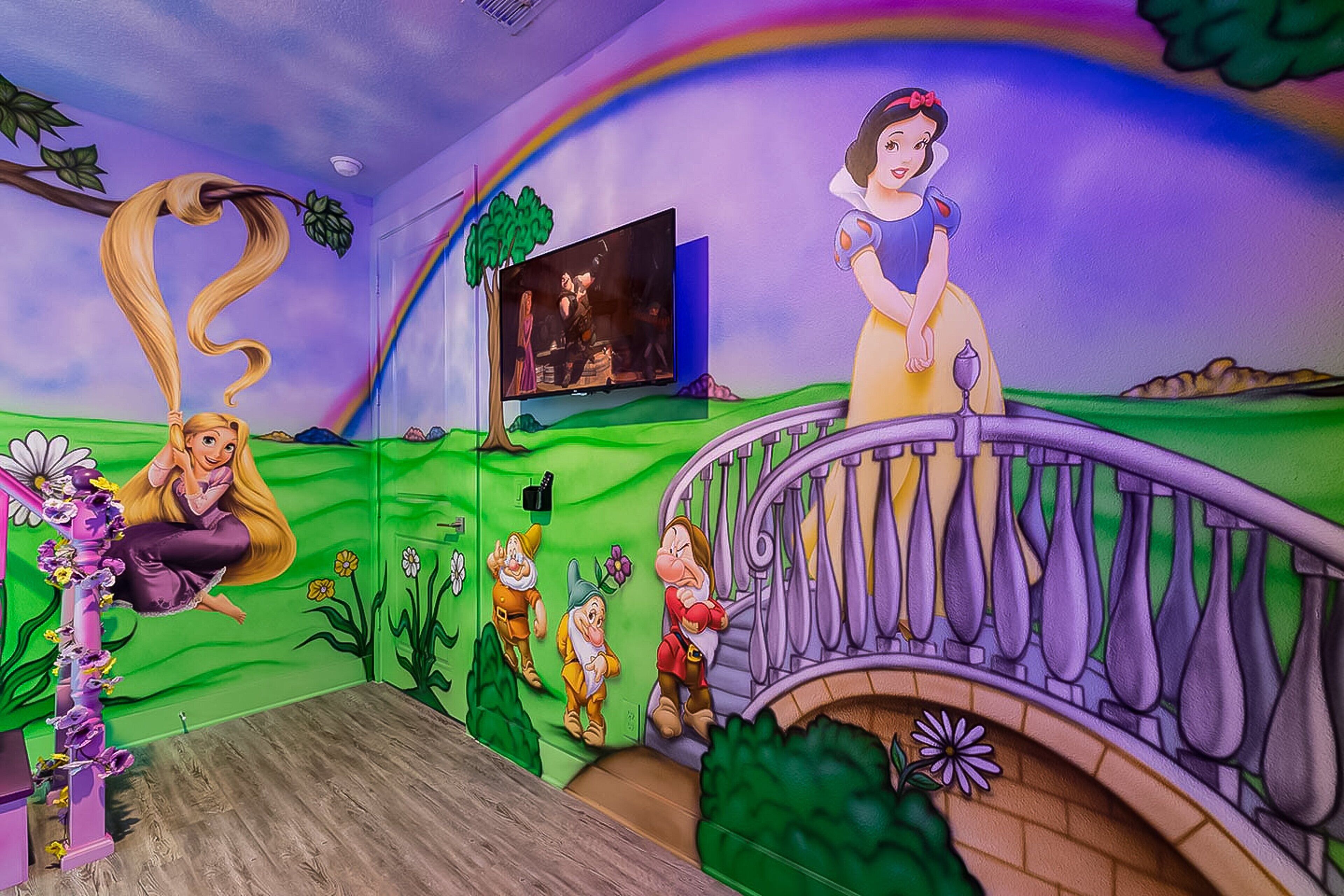 Una habitación con un mural de Blancanieves y los siete enanitos, un televisor y una escalera morada.