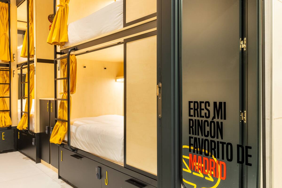 A hotel room with bunk beds, a wardrobe, and a door with a sign in Spanish.