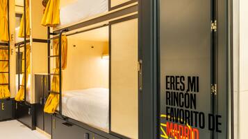 Une chambre d’hôtel avec des lits superposés, une armoire et une porte sur laquelle est affichée une pancarte en espagnol.