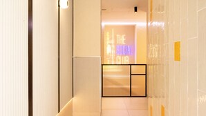 A hallway with a neon sign reading "The Social Club". - Petit Hostel Palacio Real (Madrid)