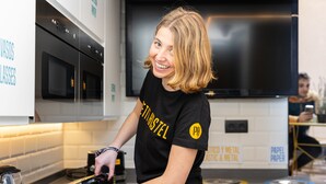 A person cooking with a sandwich press in a modern kitchen with white cabinets and a black countertop. - Petit Hostel Palacio Real (Madrid)