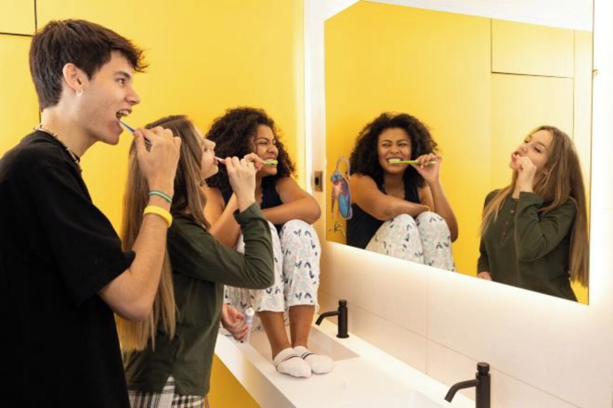 A bathroom with a yellow wall, a white sink, and a mirror.