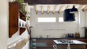Una cucina moderna con travi in legno, un'ampia finestra e una lampada a sospensione.