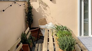 Una terrazza sul tetto con tavolo in legno, sedie, piante in vaso e luci a stringa.