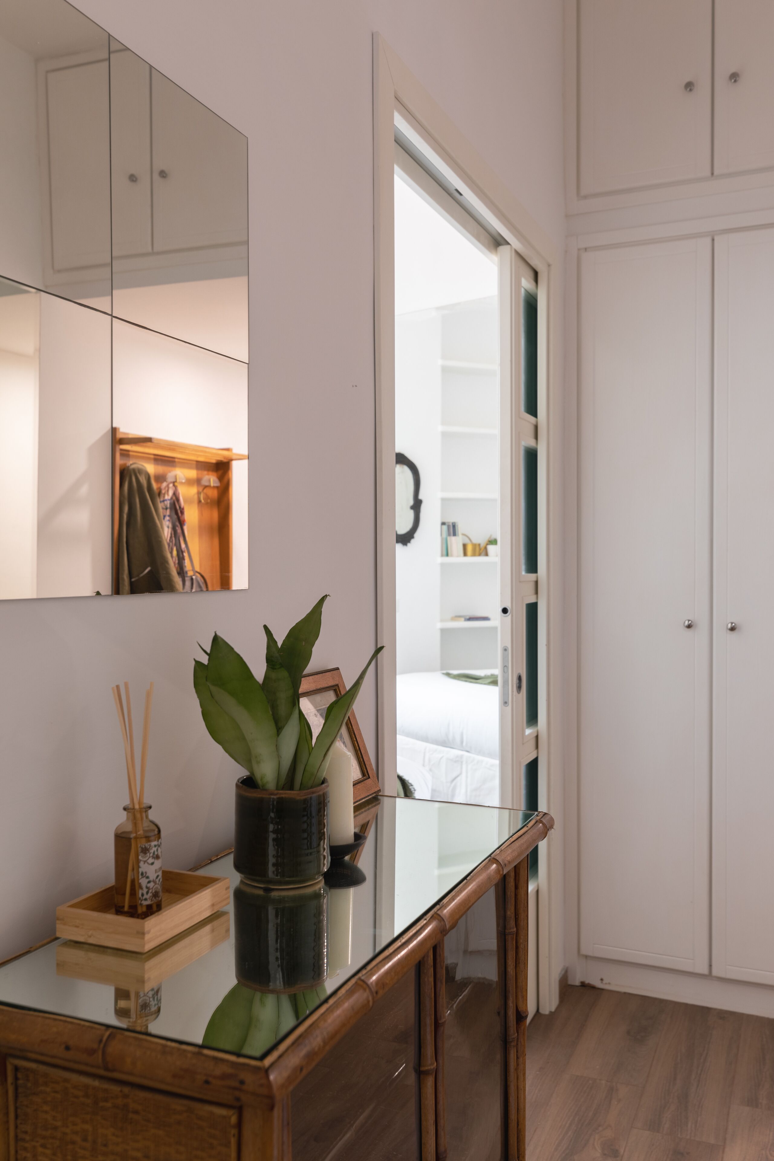 Et moderne soveværelse med et glas skrivebord, en potteplante og et garderobeskab.