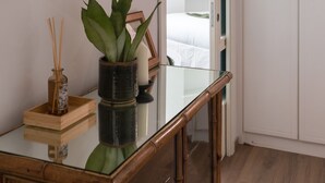 Una camera da letto moderna con una scrivania in vetro, una pianta in vaso e un armadio.