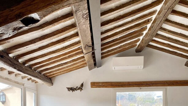 Zona pranzo con tavolo e sedie in legno, una porta in legno con tende e vista sull'esterno attraverso una finestra.