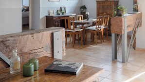 A rustic kitchen with wooden beams, a dining area with wooden chairs, and a view of a bedroom through an open door. - Penthouse in Trastevere with rooftop terrace🌱🌈 (Roma)