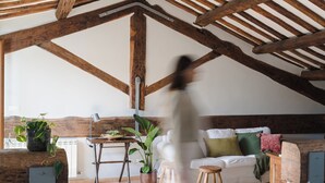 A spacious loft with exposed wooden beams, a white sofa, and potted plants. - Penthouse in Trastevere with rooftop terrace🌱🌈 (Roma)