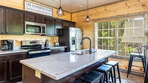 A modern kitchen with dark cabinets, stainless steel appliances, and a large island with bar stools. - Ooh LA LA, Private Indoor Pool, Arcade Game, Foosball, Free Attraction Tickets!! (Sevierville)