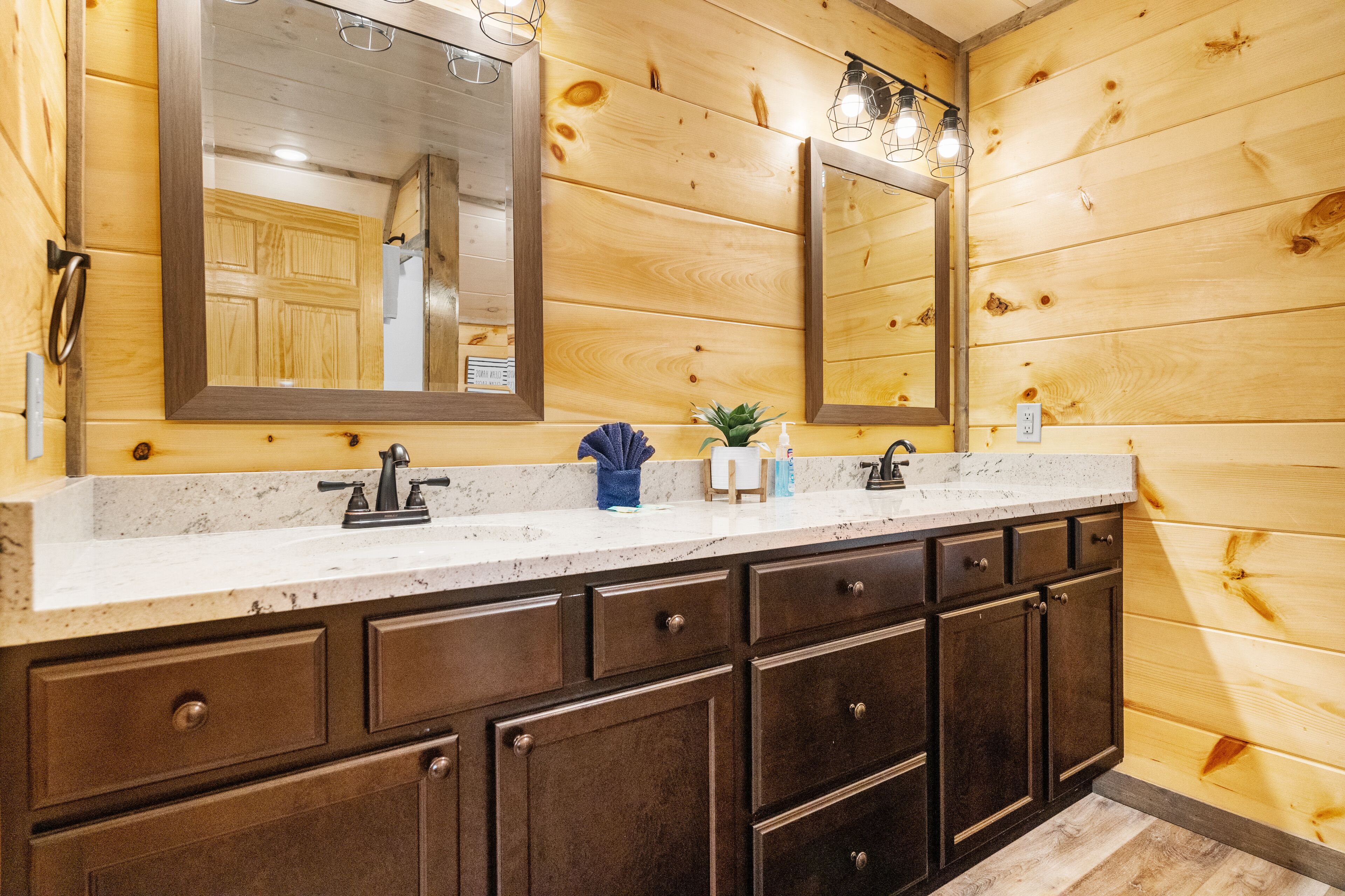 Un bagno in stile baita con specchio grande, lavabo e mobili scuri.