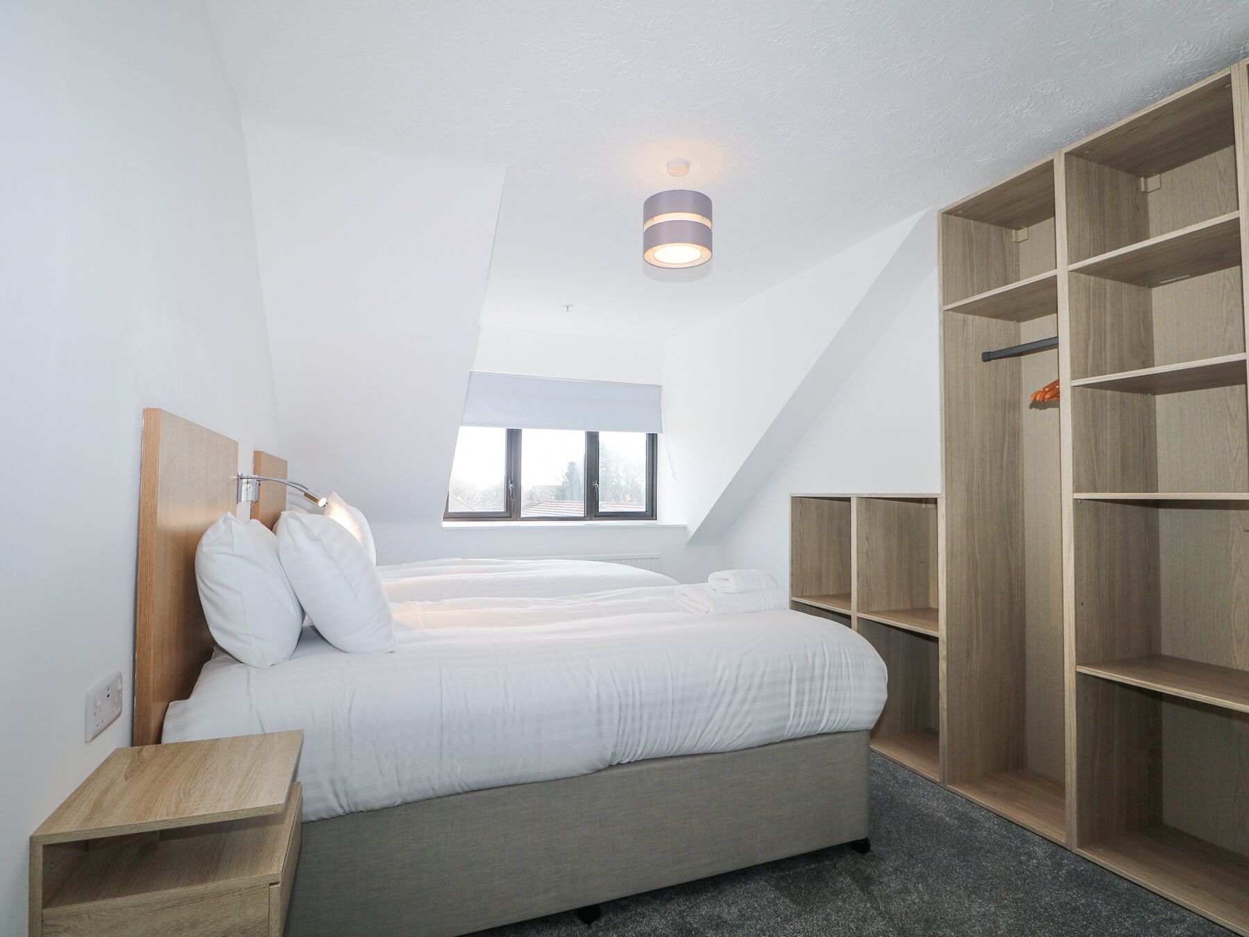 Ein Schlafzimmer mit Bett, Nachttisch, Kleiderschrank und einem Oberlicht.