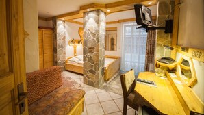A cozy room with a bed, a wooden desk, and a stone pillar. - Hotel & Restaurant Elbschetal (Wetter)