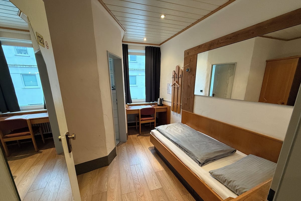 Una stanza piccola con un letto a castello, una scrivania e una finestra.