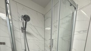 A glass-enclosed shower with a handheld showerhead and a handheld hose. - Hotel & Restaurant Elbschetal (Wetter)