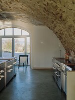 Una cocina con un amplio ventanal de arco, electrodomésticos de acero inoxidable y vistas al exterior.