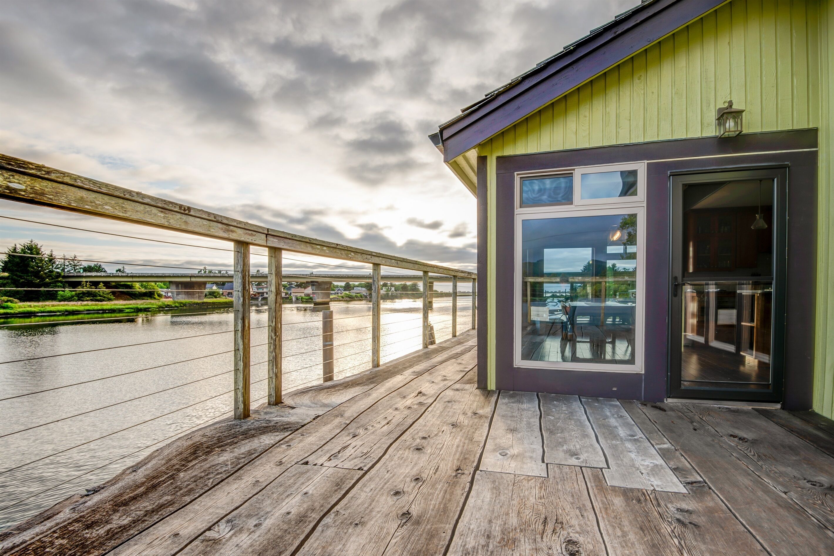 A wooden deck with a view of a river and a bridge.