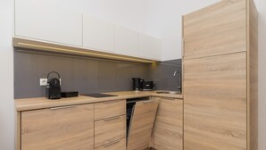 A modern kitchen with wooden cabinets, a built-in dishwasher, and a coffee maker. - Comfortable Apartment in the Center | Close to Wawel Castle | Smart TV (Kraków)