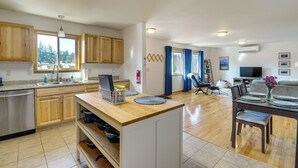 Een moderne keuken met houten kastjes, een vaatwasser en een eethoek met een tafel voor twee personen.