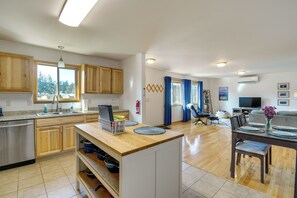 Une cuisine moderne avec des meubles en bois, un lave-vaisselle et un coin repas avec une table dressée pour deux personnes.