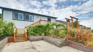 Een woonhuis met een betonnen terras, een houten trap en een houten omheining.