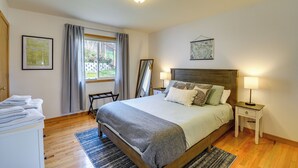 Een slaapkamer met een houten bed, twee nachtkastjes met lampen, een raam met gordijnen, en een inlijsting kaart aan de muur.