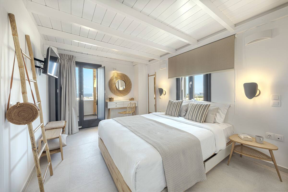 Une chambre moderne avec un grand lit, un bureau et une chaise. Une fenêtre offre une vue sur la ville.