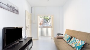 A modern living room with a flat-screen TV on a black entertainment unit, a beige sofa with colorful pillows, and a cityscape painting on the wall. - Fantastic location. San Andrés-Las Teresitas (San Andres)