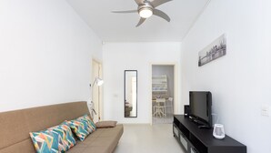A modern living room with a sofa, a TV on a black stand, and a ceiling fan. - Fantastic location. San Andrés-Las Teresitas (San Andres)