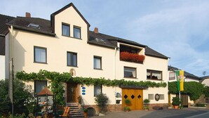 A two-story building with a gabled roof, a wooden front door, and a sign indicating a restaurant. - Komfortable, neu Renovierte Few0 im Romantischen Weingut (Leiwen)
